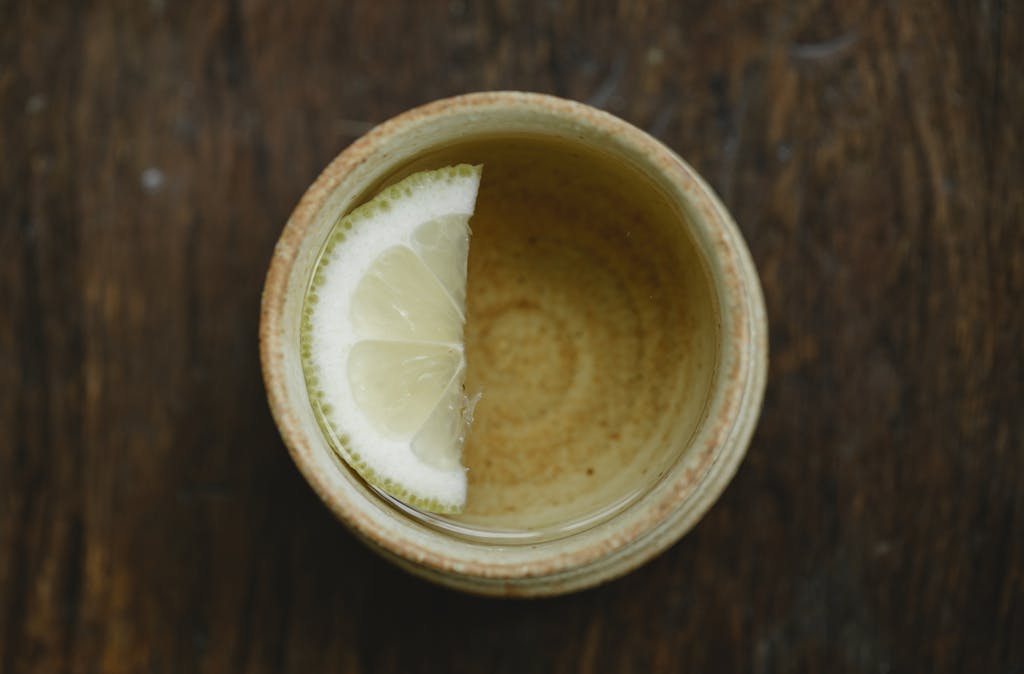 overhead view of traditional ceramic asian cup of fresh aromatic tea with lemon slice on wooden table 5946716