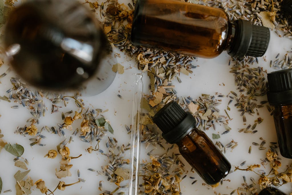 Close-Up Shot of Essential Oil Bottles and Medical Herbs on White Surface