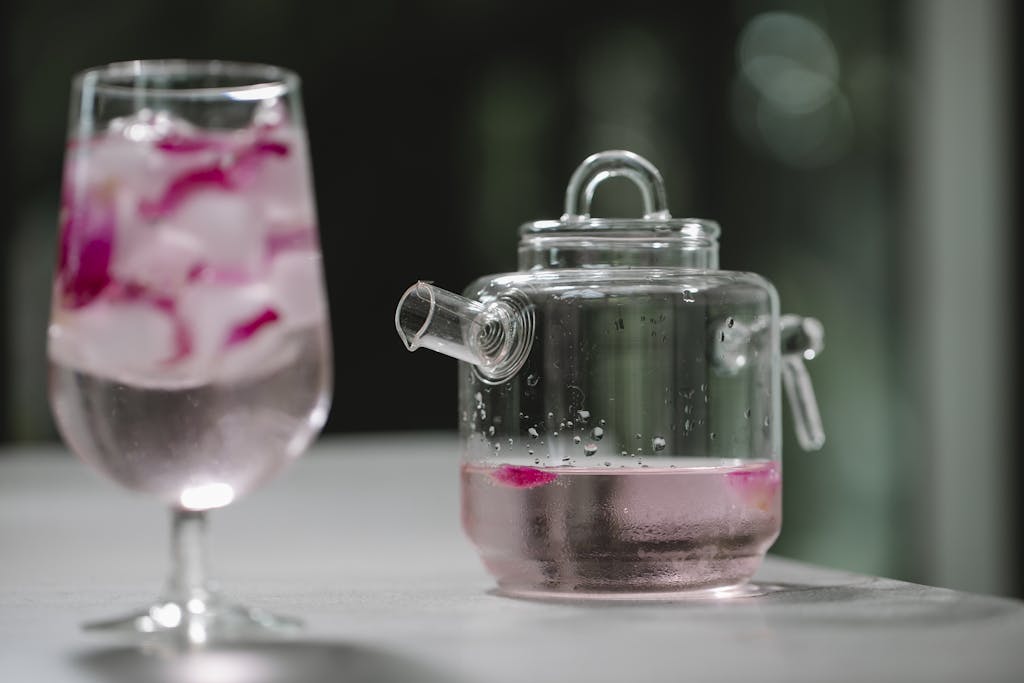 Glass and pot with cold water with rose petals