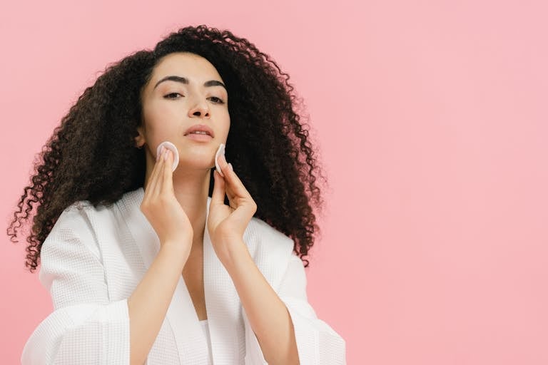 Young Woman in a Bathrobe Using Cotton Pads to Remove Makeup