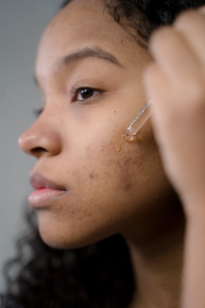 Close-up side view of a woman applying clean beauty products to her skin in a studio setting.